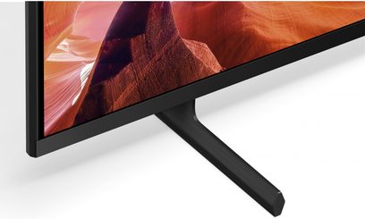 Sony 65X80L TV set fra 3/4 bagfra, fladskærm med billede af rød kløft, sort midterfod