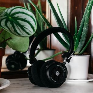 Trådløst Grado GW100 hovedsæt i sort, med læderhovedrem og -puder, placeret på et træbord ved siden af grønne planter