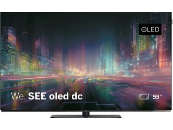 Loewe We. SEE 55 OLED dc juodas televizorius ant centrinio stovo, vaizdas iš priekio su ekranu nuo krašto iki krašto ir spalvingu miesto vaizdu