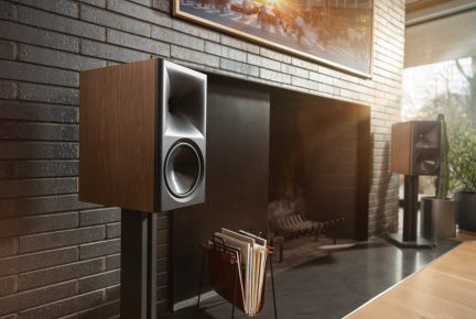 Dark brown bookshelf hi-fi speakers on stands, on either side of a television in a modern living room