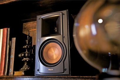 Reproduktor Klipsch RB-51 MkII v černé barvě, detailní pohled zepředu, viditelný výškový a basový reproduktor, umístěný na dřevěné polici