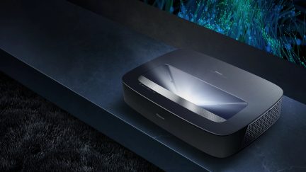 Sort laserprojektor, set ovenfra, glat overflade, sideventilationsgitter, lys udsendt opad