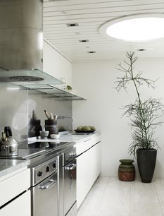 Moderne hvidt køkken med marmorbordplade, glashylder, grønne planter og indbygningsspots i loftet