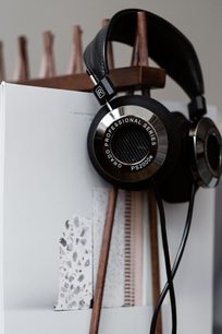 Åben hi-fi hovedtelefon Grado PS2000E i træ, hovedbøjle og ørepuder i læder, synlige transducere, placeret på en åben bog