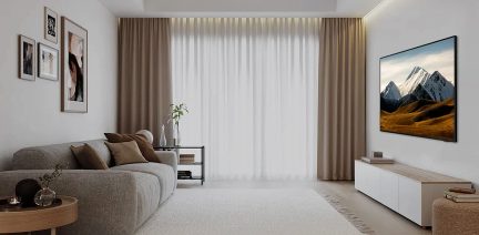 Wohnzimmer mit grauem Sofa, beigen Vorhängen, Bergbild, Regal mit Bilderrahmen, beigem Teppichboden