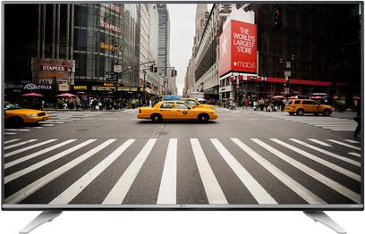 LG 55UF772V-fladskærms-TV, der viser en livlig New York-gade med gule taxier og fodgængere, set forfra, fladskærm på fod