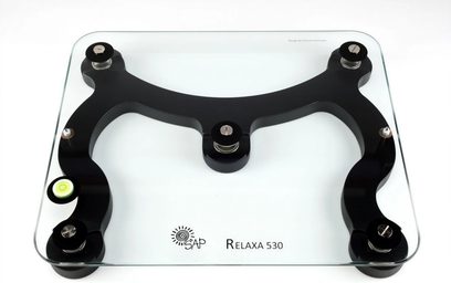 Relaxa 530, transparent hærdet glasplade til dæmpning af vibrationer med 3 justerbare sorte fødder, set oppefra