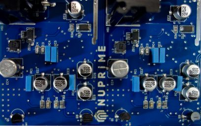 Blåt printplade med elektroniske komponenter såsom sølvfarvede kondensatorer og sorte og blå modstande
