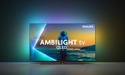 Sort glas- og metalfladskærms-tv, set forfra, med meget tynde kanter på sort centralt stativ og flerfarvet lyshalo projiceret bagud