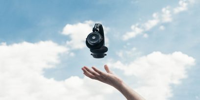 Sort Grado GW100 hovedtelefoner holdt i en udstrakt hånd mod den skydækte himmel, set nedefra
