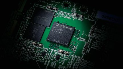 Close-up view of a green electronic board with two black chips, one marked "Qualcomm QCS407 201-AA PH9407X7"