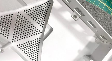 Gråt PC-kabinet, nærbillede af perforeret panel med trekantede mønstre og åben sidestruktur