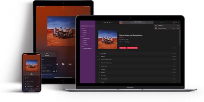 Tre elektroniske enheder: En tablet, en bærbar computer og en smartphone, der viser en musikafspilningsapp