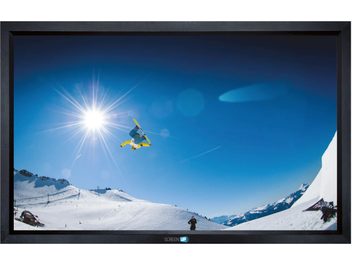 Skieur sautant dans un ciel bleu ensoleillé au-dessus d'une piste de ski enneigée dans un paysage montagneux