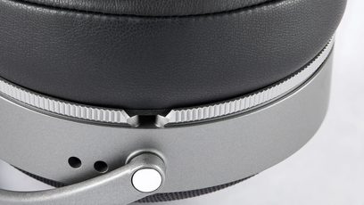 Close-up side view of the black leather-textured earpad, matte grey metal housing with a knurled ring and pivoting hinge, of the Audeze LCD-S20 closed-back wired hi-fi headphones