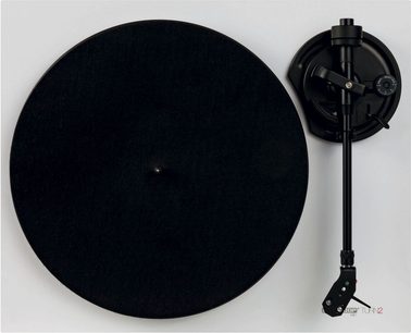 Platine vinyle noire et bras de lecture noir sur fond blanc. Vue de dessus