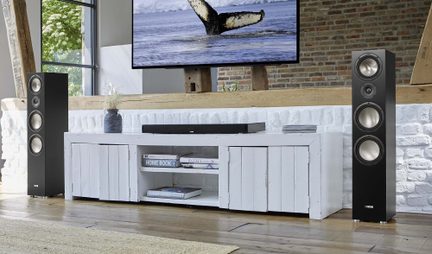 Zwarte Canton vloerstaande luidsprekers aan weerszijden van een wit tv-meubel in een lichte, moderne woonkamer