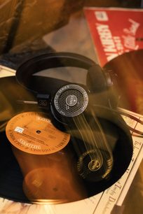 Åben Grado SR125x hovedtelefon med runde transducere, læderbetrukket hovedbøjle og spiralformet kabel, placeret på vinylplader