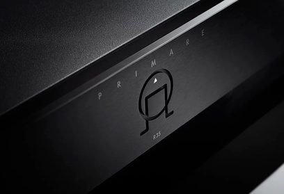 Čierna stereo predzosilňovač Primare R35, čiastočný pohľad spredu, zväčšené logo a otočný volič