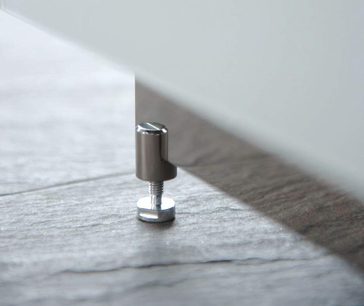 Cylindrisk, kromet metalfod til møbler, set fra siden, placeret på en gråt tekstureret overflade
