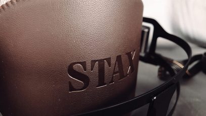 Cuffia audio STAX SR-X9000 in primo piano sul lato sinistro, in pelle marrone scuro con l'iscrizione "STAX" incisa