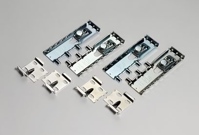 Sæt med fem monteringsskinner og fem matchende clips i sølvfarvet metal, med indhak og knapper, set i let fugleperspektiv