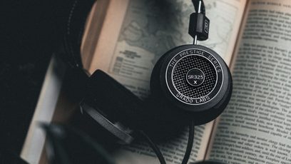 Avoin Grado SR325x hi-fi-kuulokkeet ovat avoimen kirjan päällä, sivulta kuvattuna, oikea kuulokeloke etualalla