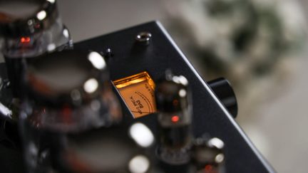 Sort rørlydforstærker med synlige rør og orange baggrundsbelyst analogt VU-meter, nærbillede