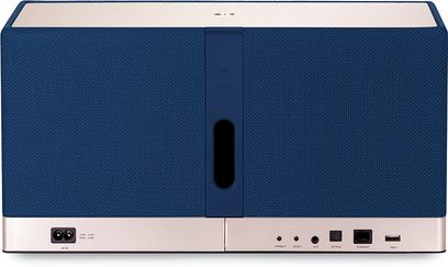 Triangle AIO 3, vue arrière, enceinte tissu bleu, évent central, bandeau métallique, ports AC, AUX, optique, Ethernet, USB