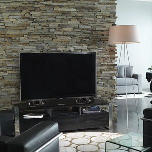 Sort Klipsch SB-3 soundbar under et fjernsyn, placeret på et mørkt træmøbel foran en stenmur
