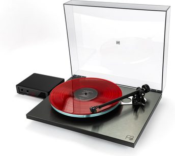 Platina de vinil hi-fi Rega Planar 3 RS com prato transparente, disco vermelho, braço de leitura preto, tampa aberta, caixa preta adjacente
