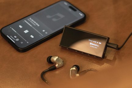 player audio Bluetooth negru cu smartphone și căști intraauriculare argintii pe masă din piele