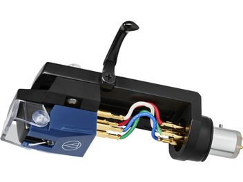 Šoninis vaizdas: ant Audio Technica AT-VM520xEB/H galvutės sumontuota kasetė, juodos ir mėlynos spalvos plastikinis korpusas su permatomu dangteliu, auksiniai jungikliai ir spalvoti vidiniai laidai, juodas svirtis ir sidabrinės spalvos cilindrinė metalinė bazė