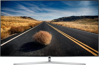 Flad Samsung UE49KS8000TXZF TV-skærm, der viser en lige vej, der krydser et bakkelandskab i en ørken under en blå, let skyet himmel