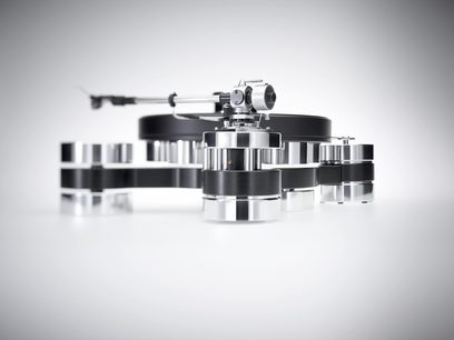 Transrotor Dark Star Silver Shadow RB330 hi-fi vinylplatespiller i sølvfarget og svart aluminium, lav front-trekvartsvinkel, med tykt rundt tallerken, rørformet tonearm og chassis med flere sylindriske føtter