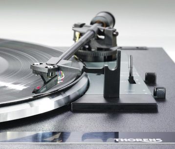 Thorens TD 170-1 sidabrinės spalvos vinilinių plokštelių grotuvas, matomas iš viršaus su nuskaitymo galvute, adatėle ir valdymo rankenėlėmis, padėtas ant juodo pagrindo