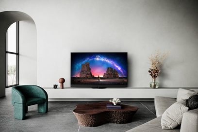 Panasonic TX-65LZ2000E-fladskærms-tv, der viser et farverigt landskab, i en moderne stue med sofa og minimalistisk indretning