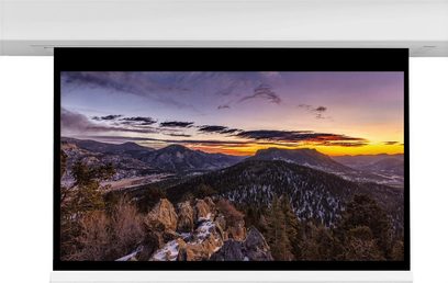 Horské panorama při západu slunce s barevnou oblohou, zalesněným údolím a skalami v popředí