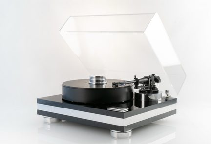 Prato de vinil preto e prata em metal e acrílico, apresentando um prato circular preto espesso, um braço de leitura lateral direito e uma tampa transparente levantada, apoiado em pés cilíndricos metálicos, vista de três quartos frontal direita