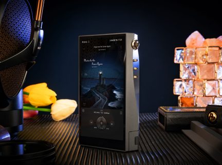 Lettore audio portatile in metallo grigio, schermo touch, vista a tre quarti, rotella del volume dorata e tre pulsanti laterali