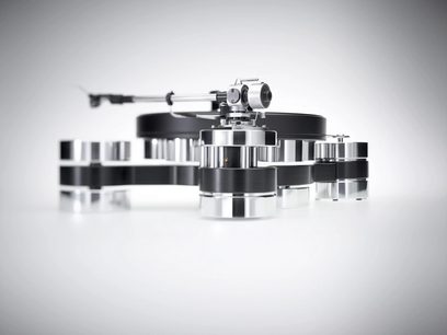 Transrotor Dark Star Silver Shadow RB330 hi-fi vinylplatespiller i sølvfarget og svart aluminium, lav front-trekvartsvinkel, med tykt rundt tallerken, rørformet tonearm og chassis med flere sylindriske føtter