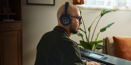 Sort, circumauralt headset i plastik og metal med åbent gitter, set i profil på en persons hoved