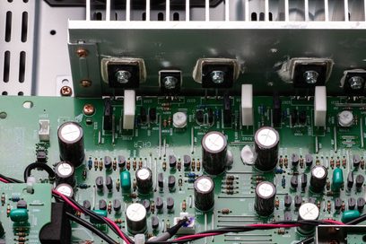 Nærbilde av innsiden av en svart Marantz PM6007 hi-fi stereoanlegg som viser de elektroniske komponentene på et grønt kretskort
