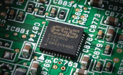 Integrovaný obvod ESS ES9080Q černé barvy namontovaný na zelené elektronické desce s SMD součástkami okolo
