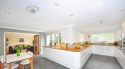 Cuisine moderne avec armoires blanches, comptoirs en bois, appareils en acier inoxydable et plafond avec spots encastrés