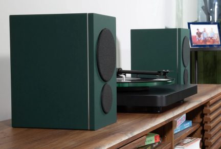 Pár tmavě zelených hi-fi reproduktorů s černými reproduktory po obou stranách černého gramofonu