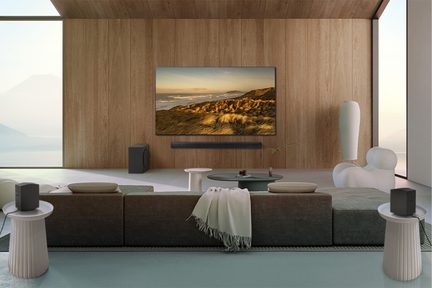 Vægmonteret fladskærms-tv, der viser et bjergrigt kystlandskab i en moderne stue med sofa, sofaborde og dekorative vaser