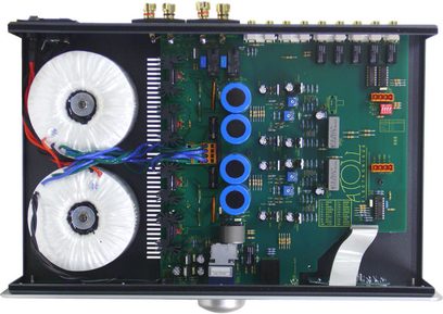 Indvendigt syn af en sort Atoll Electronique IN100SE hi-fi stereoforstærker med printplader, elektroniske komponenter og to toroidale transformere