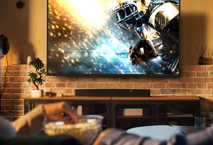 Schwarze Soundbar unter großem 4K-Fernseher in Backstein-Wohnzimmer, Heimkino-Atmosphäre mit Sport