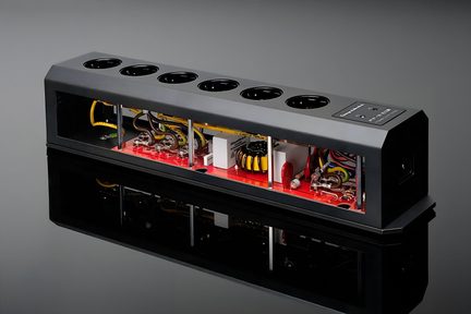 Rechteckiger schwarzer Block mit 6 runden Steckdosen oben, offene Seiten, die elektronische Komponenten auf einer roten Basis zeigen